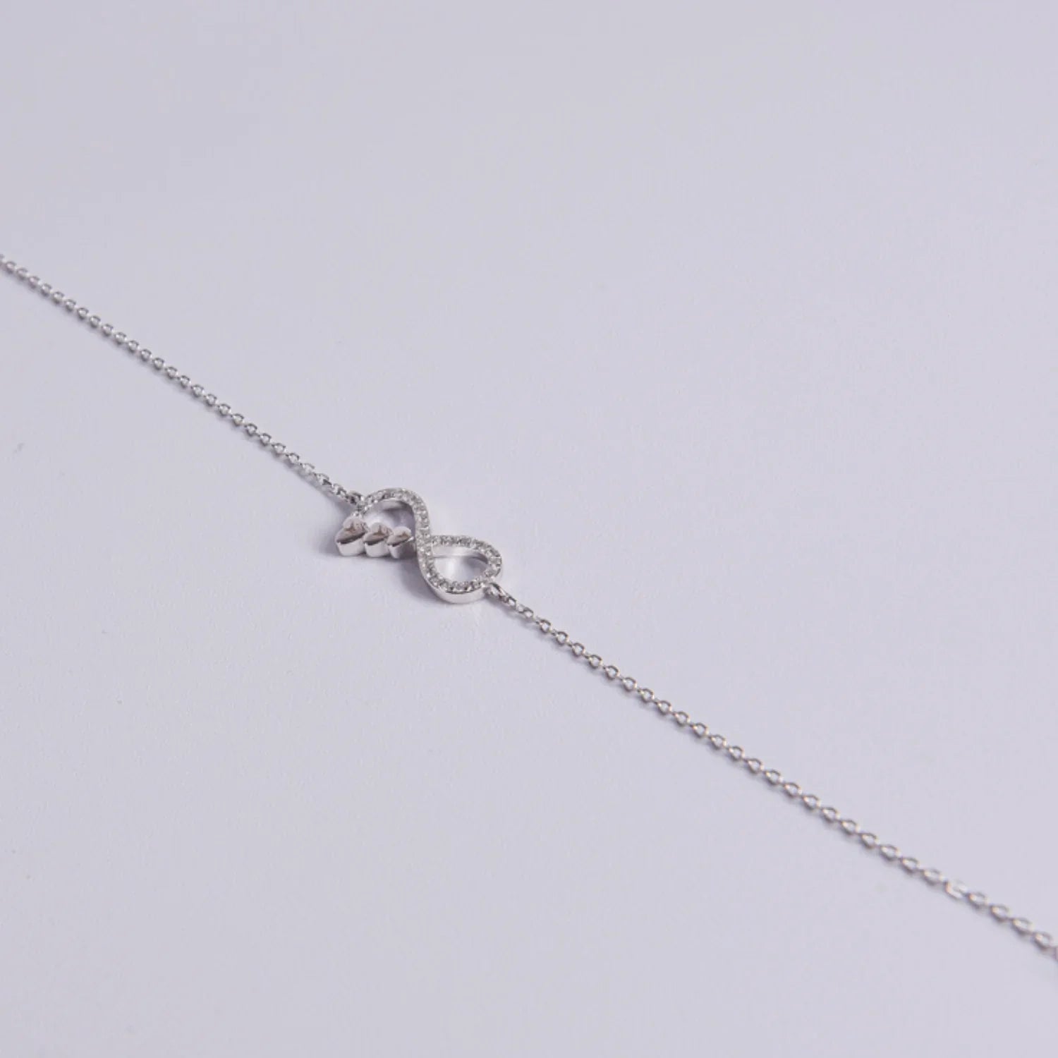 Cadena de mano plata de ley diseño infinito, detalle tres corazones y cierre ajustable con colgante final, joyería hipoalergénica.