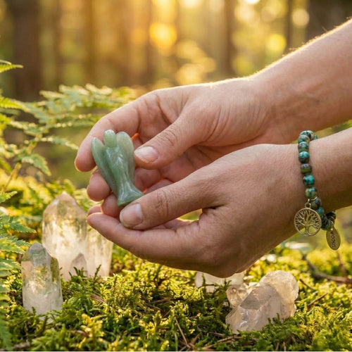 Manos sosteniendo con delicadeza un Ángel de la Guarda de Aventurina Verde en un bosque iluminado. Amuleto de piedra natural para la sanación y la conexión espiritual.