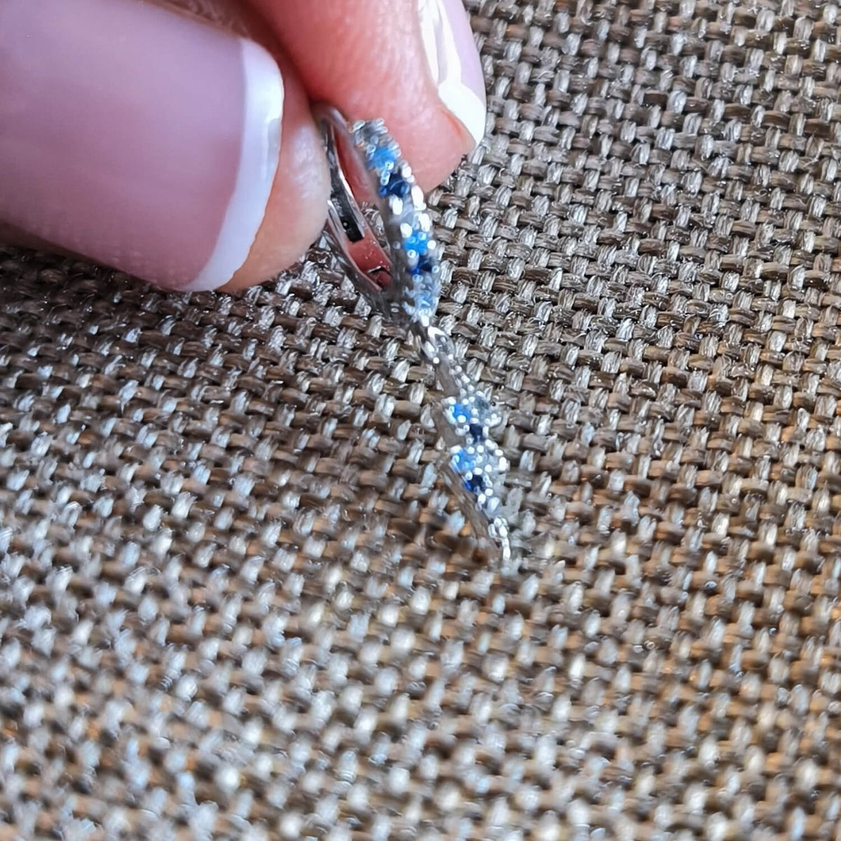 Detalle de aro de plata 925 con circonitas azules y dije de rayo colgante, joyería Aura Plena