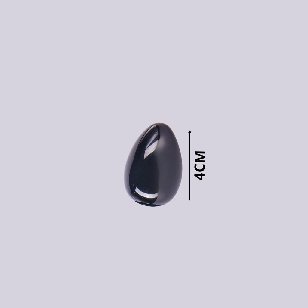 Guía de tamaño del huevo de piedra Obsidiana indicando 4 cm de altura. Mineral negro pulido sobre fondo blanco.