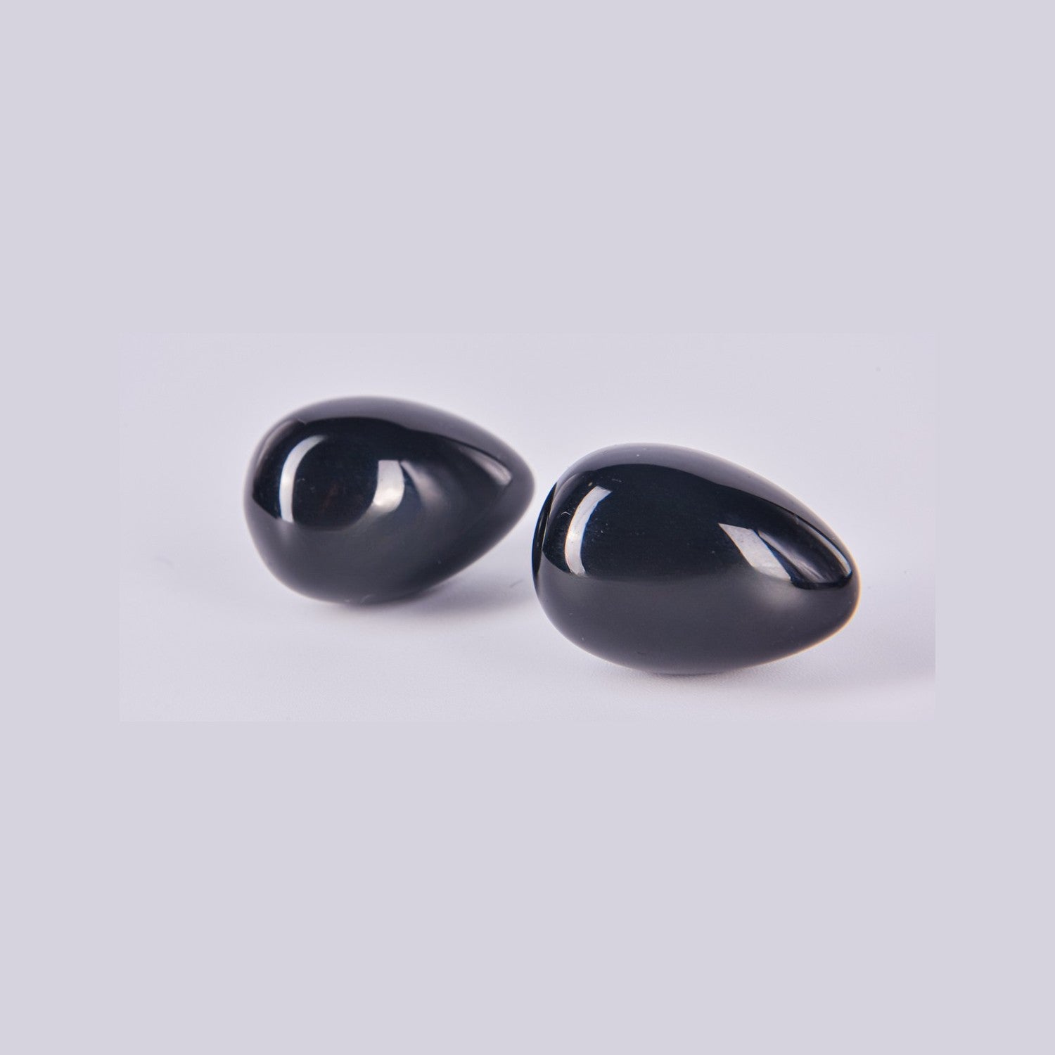 Pareja de huevos de Obsidiana Negra mostrando su superficie lisa, brillante y reflectante como un espejo negro.