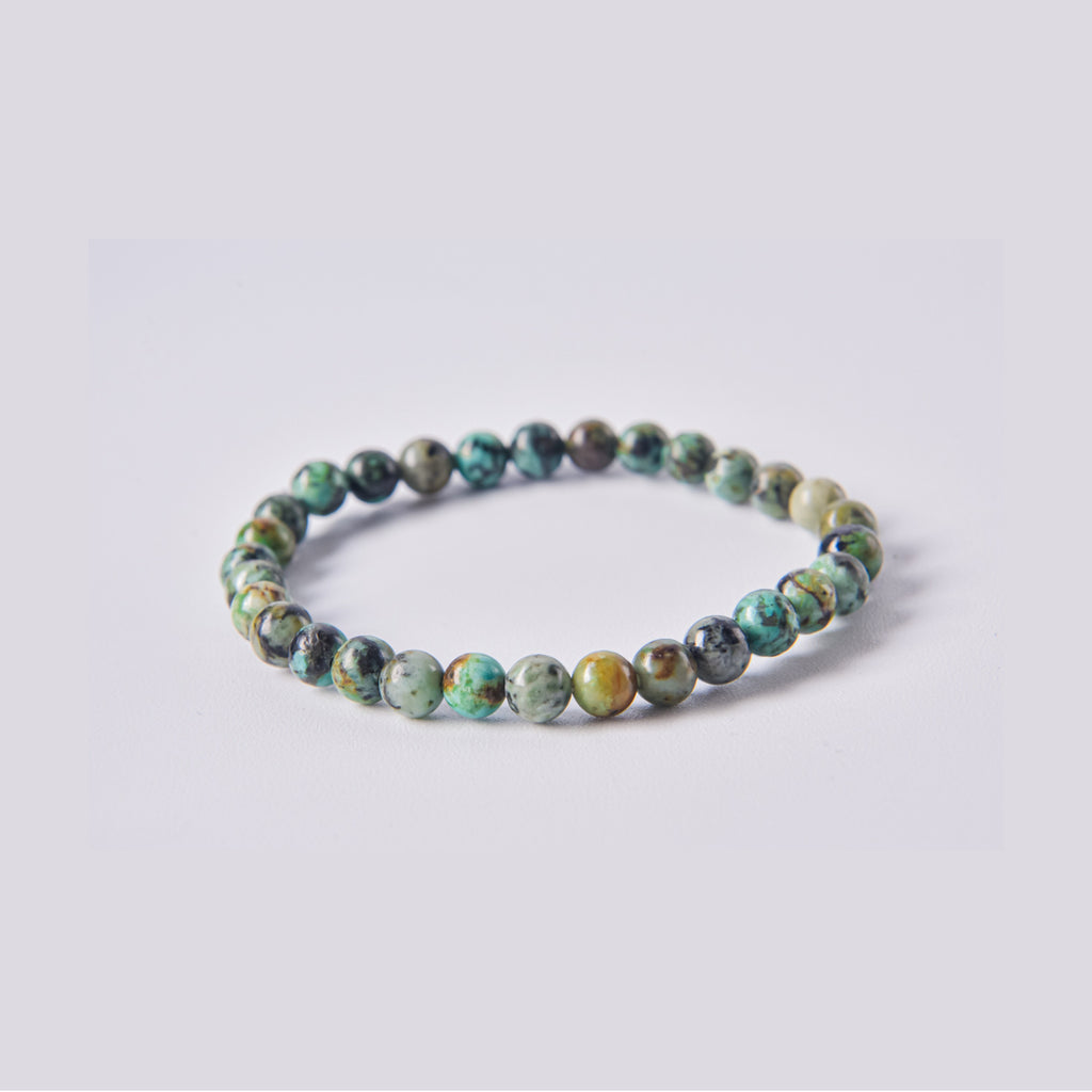 Pulsera elástica de bolas de Jaspe Turquesa Africana. Detalle de las vetas naturales negras sobre base verde azulada. Disponible en varios tamaños.
