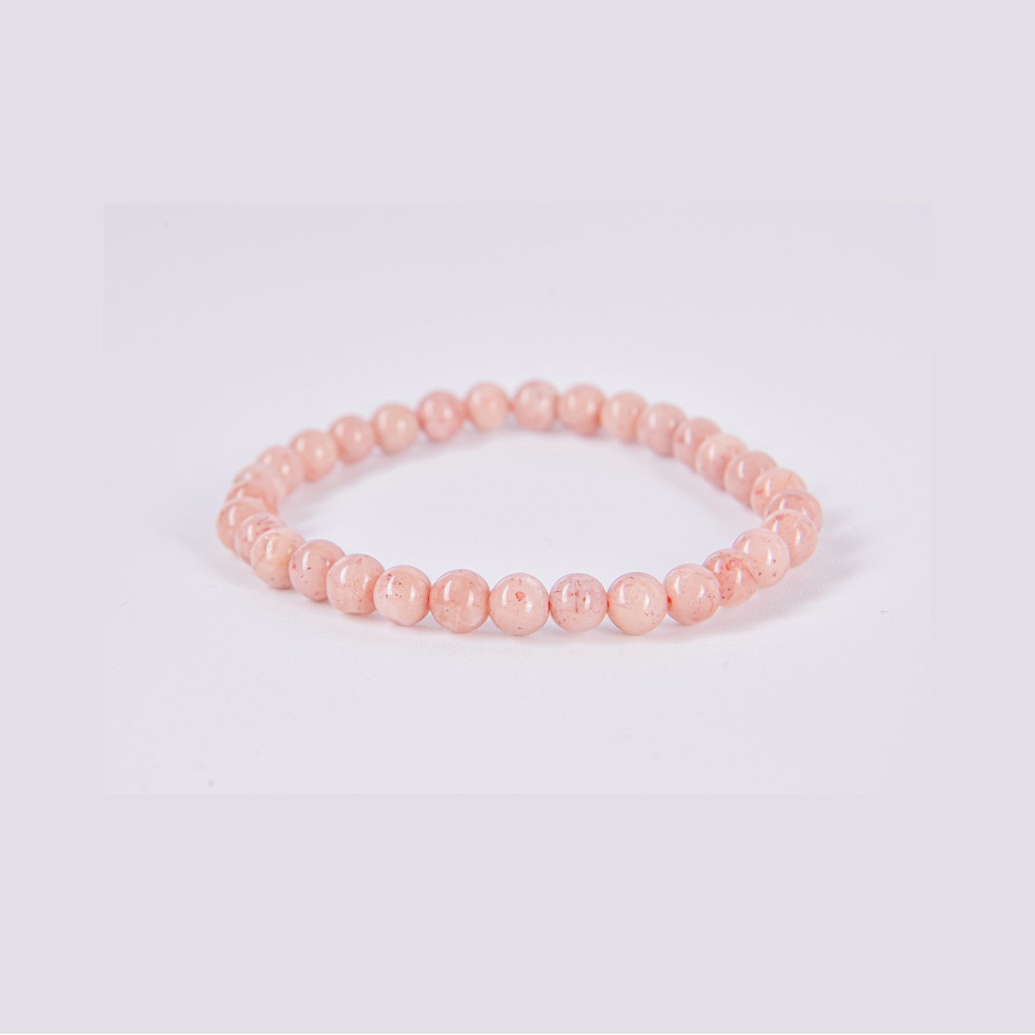 Pulsera elástica de bolas redondas de Piedra Sol natural sobre fondo blanco. Detalle del color naranja melocotón y las inclusiones brillantes típicas del mineral.