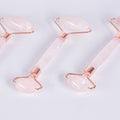 Detalle de masajeadores faciales de Cuarzo Rosa natural con acabados en metal color cobre (Rose Gold). Primer plano de los cabezales dobles de piedra auténtica.
