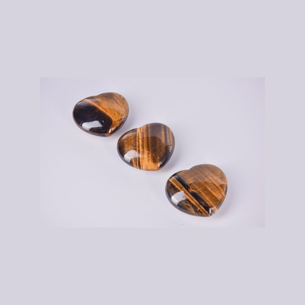 Tres corazones de Ojo de Tigre mostrando las bandas naturales doradas y marrones. Detalle del pulido brillante y el efecto óptico de la piedra.