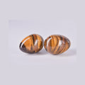 Pareja de piedras huevo de Ojo de Tigre mostrando las bandas naturales marrones y doradas y el efecto de brillo sedoso (chatoyancia).