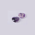 Dos piedras corazón de Amatista natural mostrando la variedad de patrones: uno morado profundo y otro con vetas blancas de cuarzo.